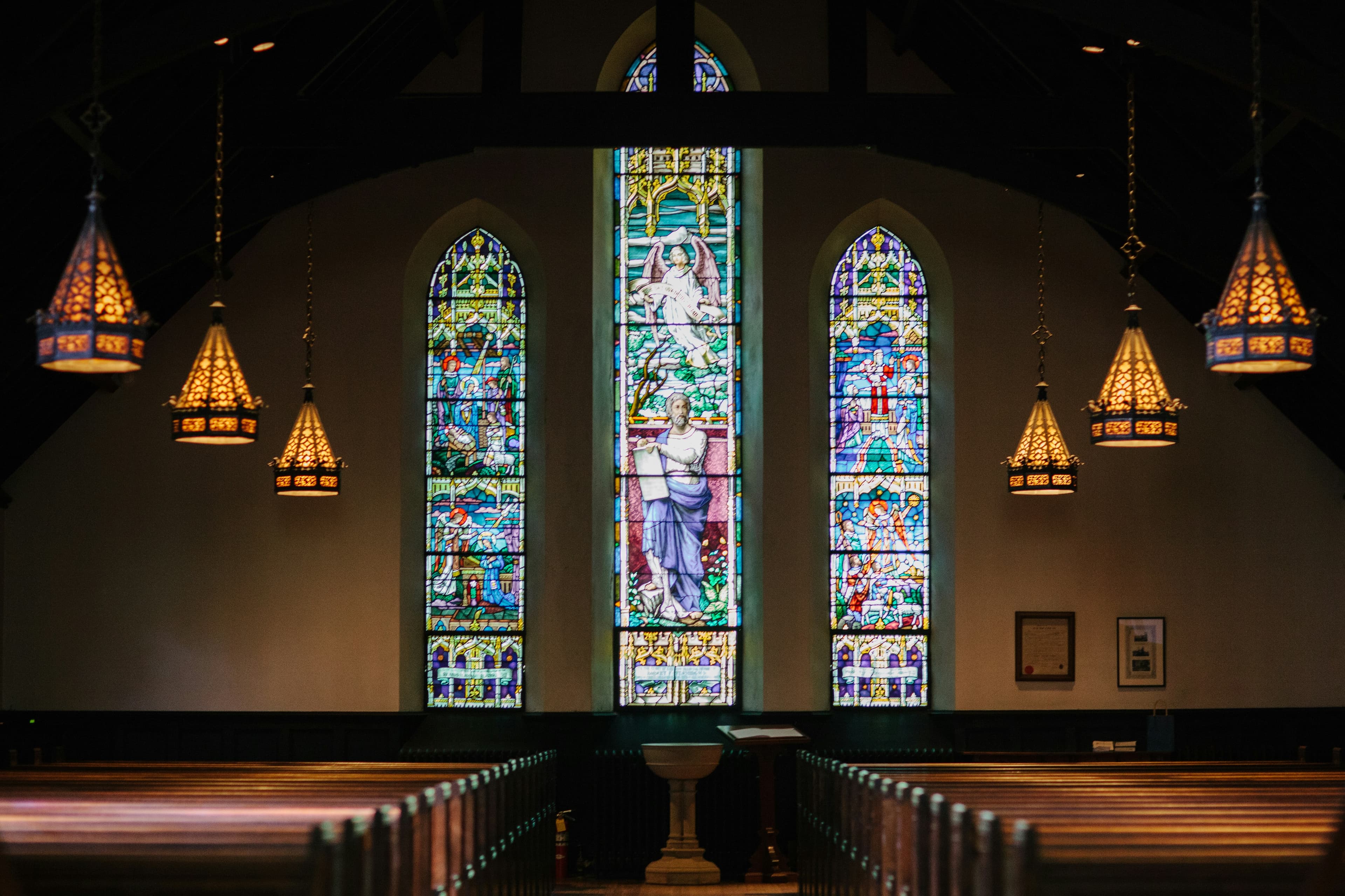 Vitraux colorés d’une église illuminés dans la pénombre de la nef